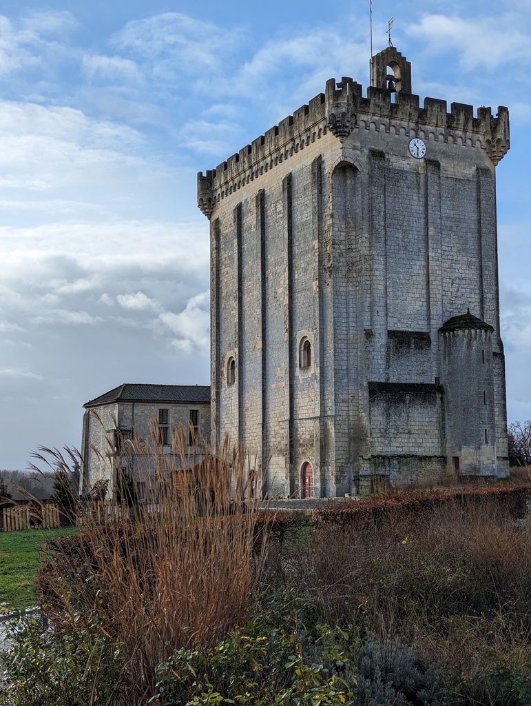A stone tower with a clock and battlements stands 