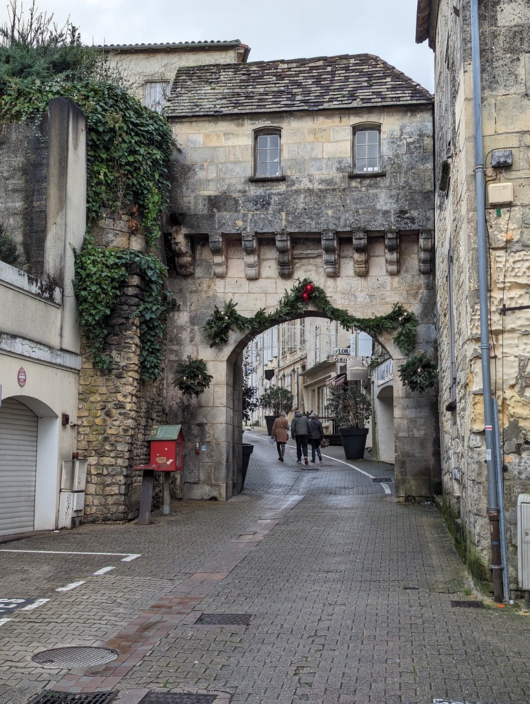 A cobblestone street leads through an old stone ar