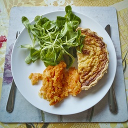 A plate of quiche and salad with mashed potatoes.