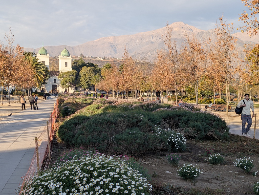 A scenic park with a distant mountain and church towers in the background.