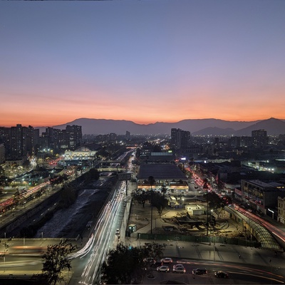 An orange sunset over a city skyline with mountains in the distance.